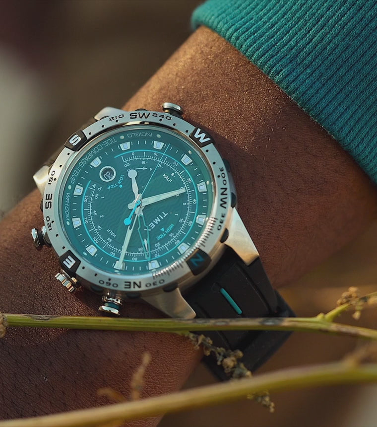 Timex Expedition Tide-Temp-Compass watch with a turquoise dial and black strap on a person’s wrist outdoors. The camera slowly pans and zooms across the watch, highlighting its analog display, compass bezel, and rugged design before ending with a detailed close-up of the watch face being adjusted by hand.