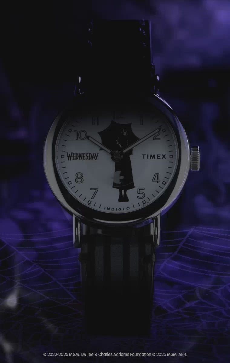 Video for the Timex x Wednesday Weekender watch collection. The video features moody, gothic visuals inspired by the Netflix "Wednesday" series. It showcases close-up shots of the watch with a striped leather strap and a dial featuring Wednesday Addams' silhouette holding an umbrella. Transitions highlight the Indiglo backlight effect, which reveals hidden gothic gate artwork on the dial.