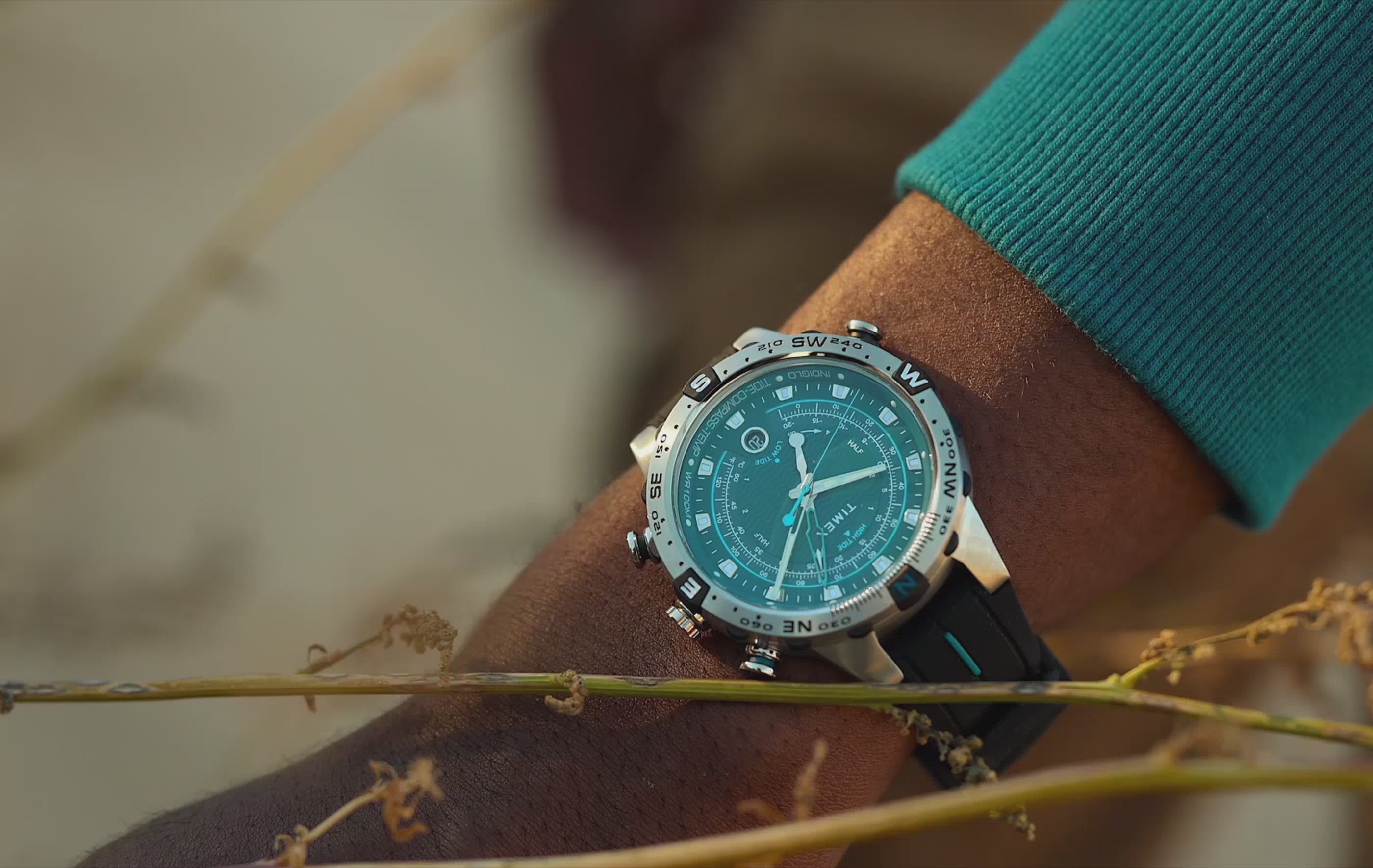 Timex Expedition Tide-Temp-Compass watch with a turquoise dial and black strap on a person’s wrist outdoors. The camera slowly pans and zooms across the watch, highlighting its analog display, compass bezel, and rugged design before ending with a detailed close-up of the watch face being adjusted by hand.