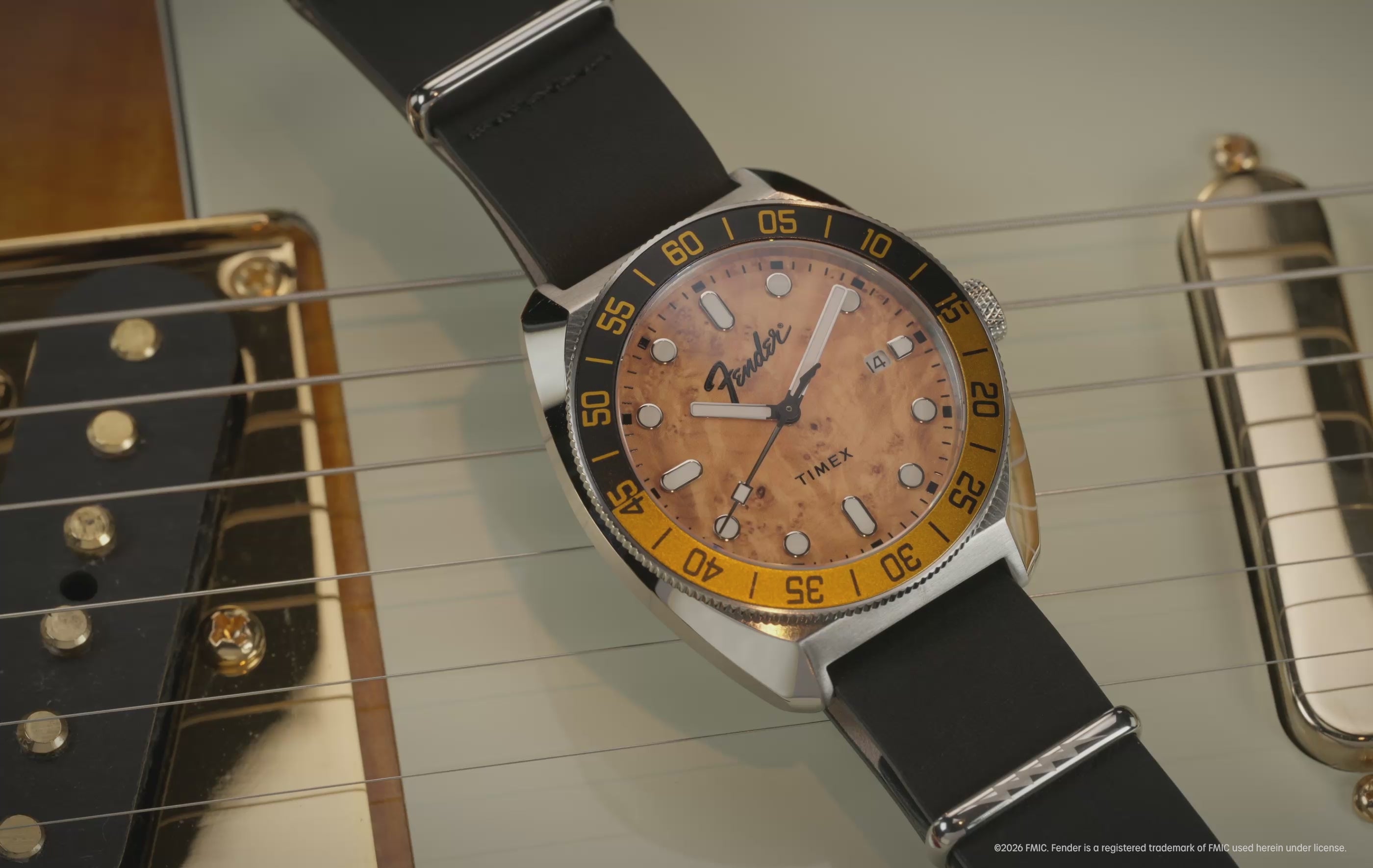 Fender x Timex Automatic watch with a wood-grain dial, black strap, and exhibition case back displayed alongside Fender guitars.