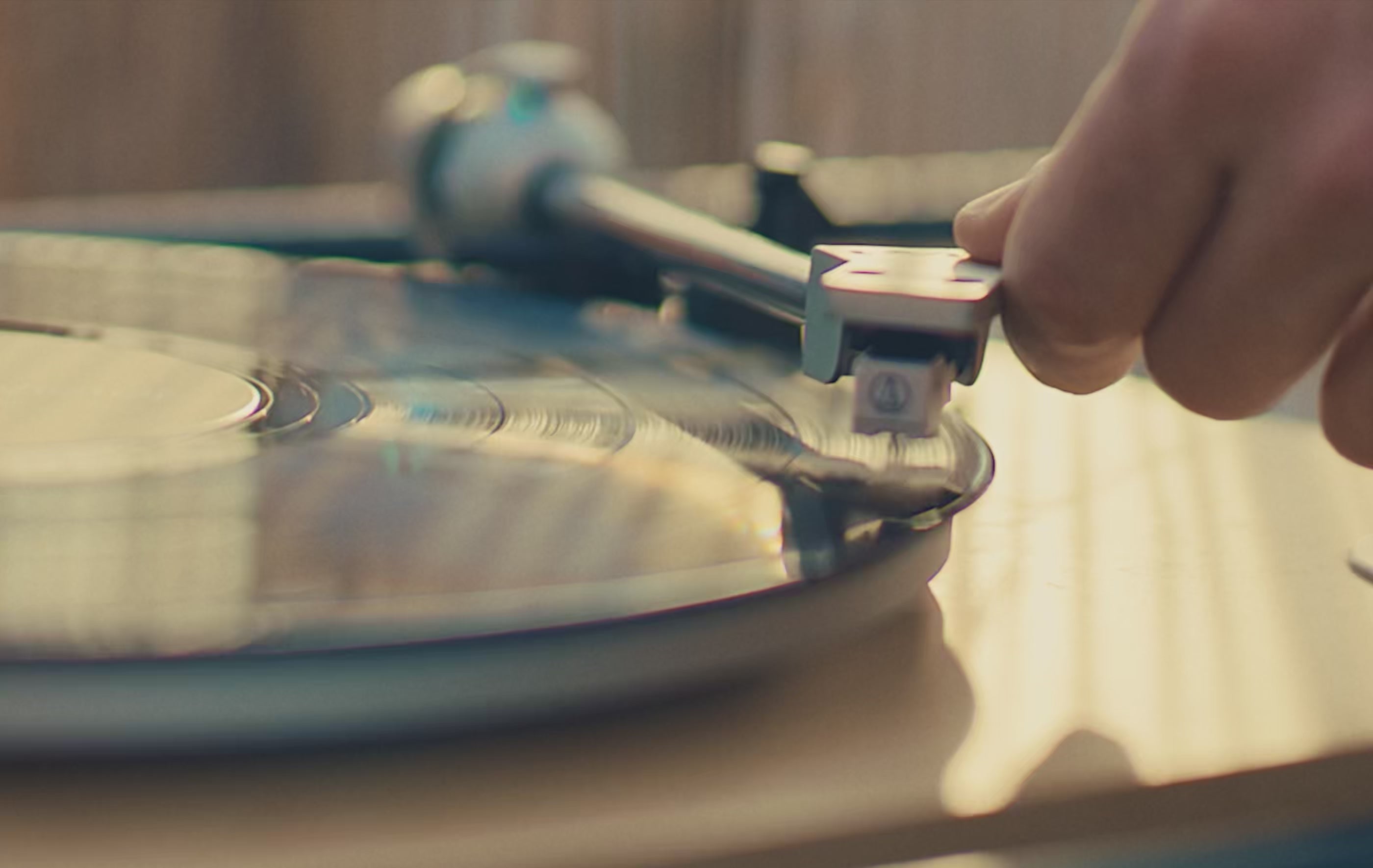 A warm holiday-themed montage featuring close-up shots of a spinning vinyl record, friends toasting drinks outdoors at dusk, and a detailed close-up of a Timex Waterbury chronograph watch glinting in soft light. The video ends with a nighttime sky and the message ‘Time is a Gift.’