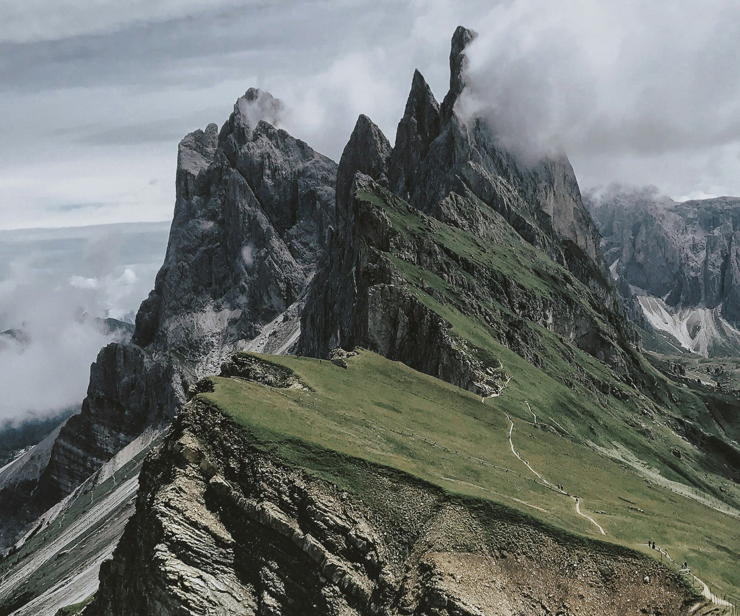 A photo of rocky mountain with clouds above the top of it